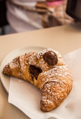 Delicioso croissant relleno de chocolate y espolvoreado con azúcar pastelera, similar al croissant de almendras.