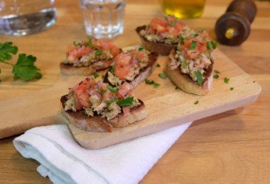 Montaditos con atún, tomate fresco y hierbas, servidos en tabla