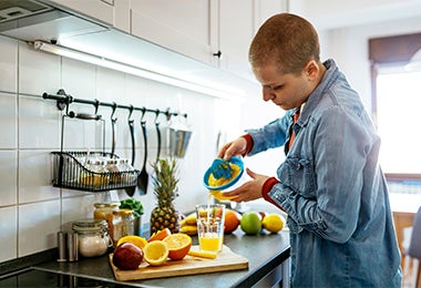 Mujer usando un exprimidor de cítricos para preparar jugo de naranja