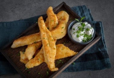 Palitos de pollo amontonados con un dip, una exquisita variante de los palitos de queso.