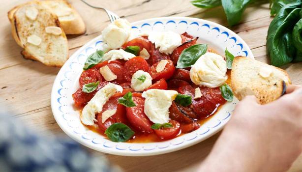 Ensalada caprese con tomate, queso, albahaca y pan en un plato