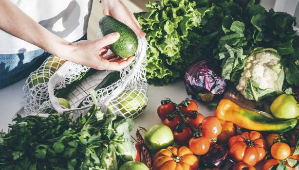 Una persona sacando productos orgánicos, frutas y verduras de una bolsa 