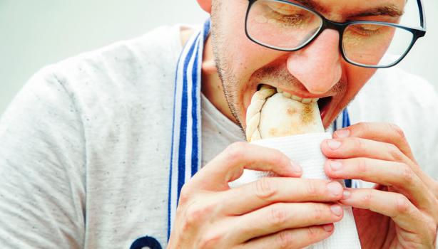 Hombre degustando unas deliciosas empanadas de hojaldre.