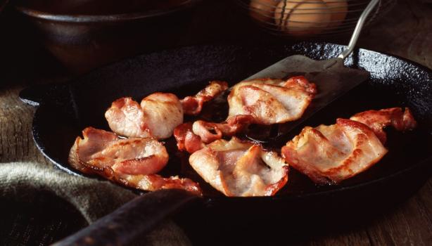 Deliciosa panceta cortada siendo fritada en un sartén.