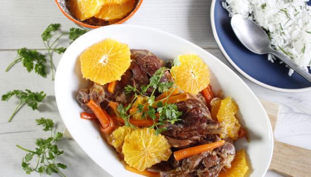 Plato de cerdo con salsa de naranja, acompañado de rodajas de naranja