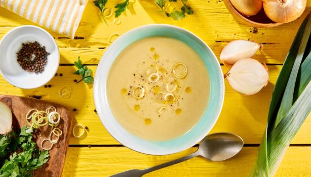 Vichyssoise en un tazón, mesa amarilla con ingredientes frescos